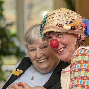Auf dem Bild lachen eine Seniorin und eine Clownin vergnügt in die Kamera.Foto: Andreas Weise / factum-fotojournalismus.de
